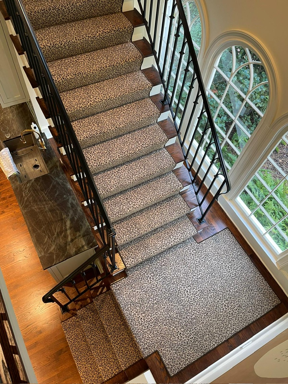 Cheetah print stair runner on dark wood stairs with iron railing
