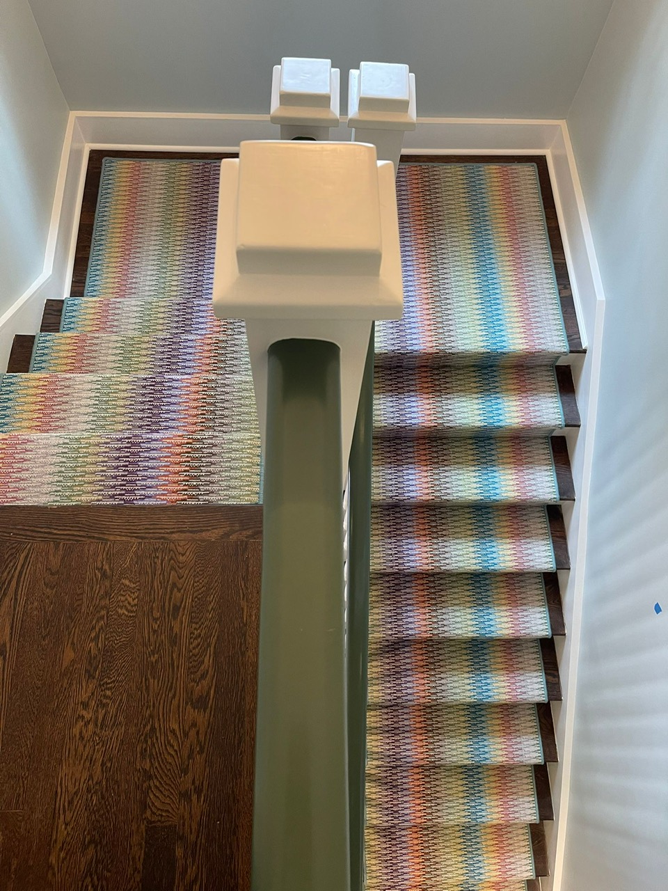 Colorful Missoni-style woven stair runner on curved white staircase