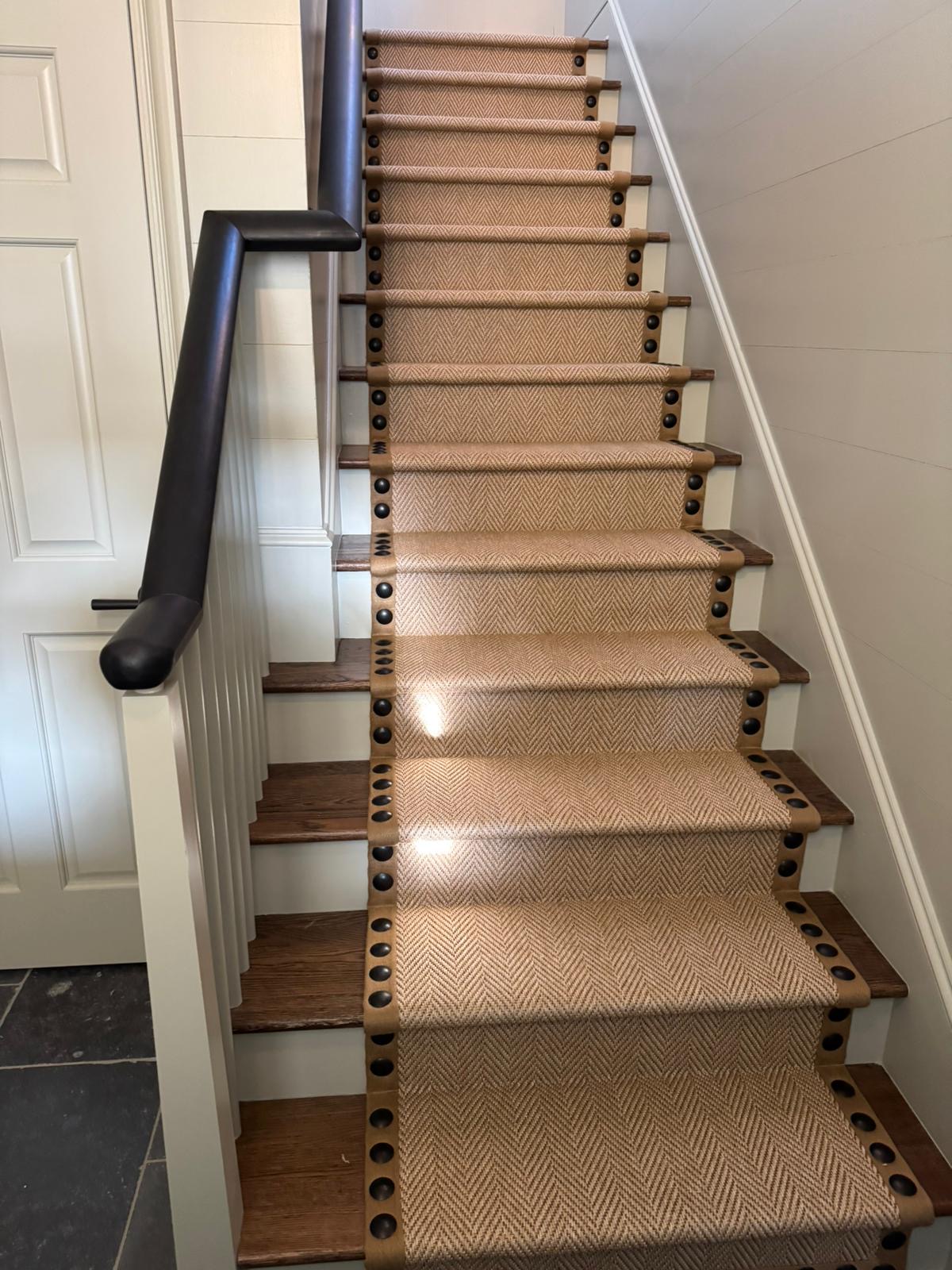 Natural sisal runner with nailhead trim on dark wood stairs