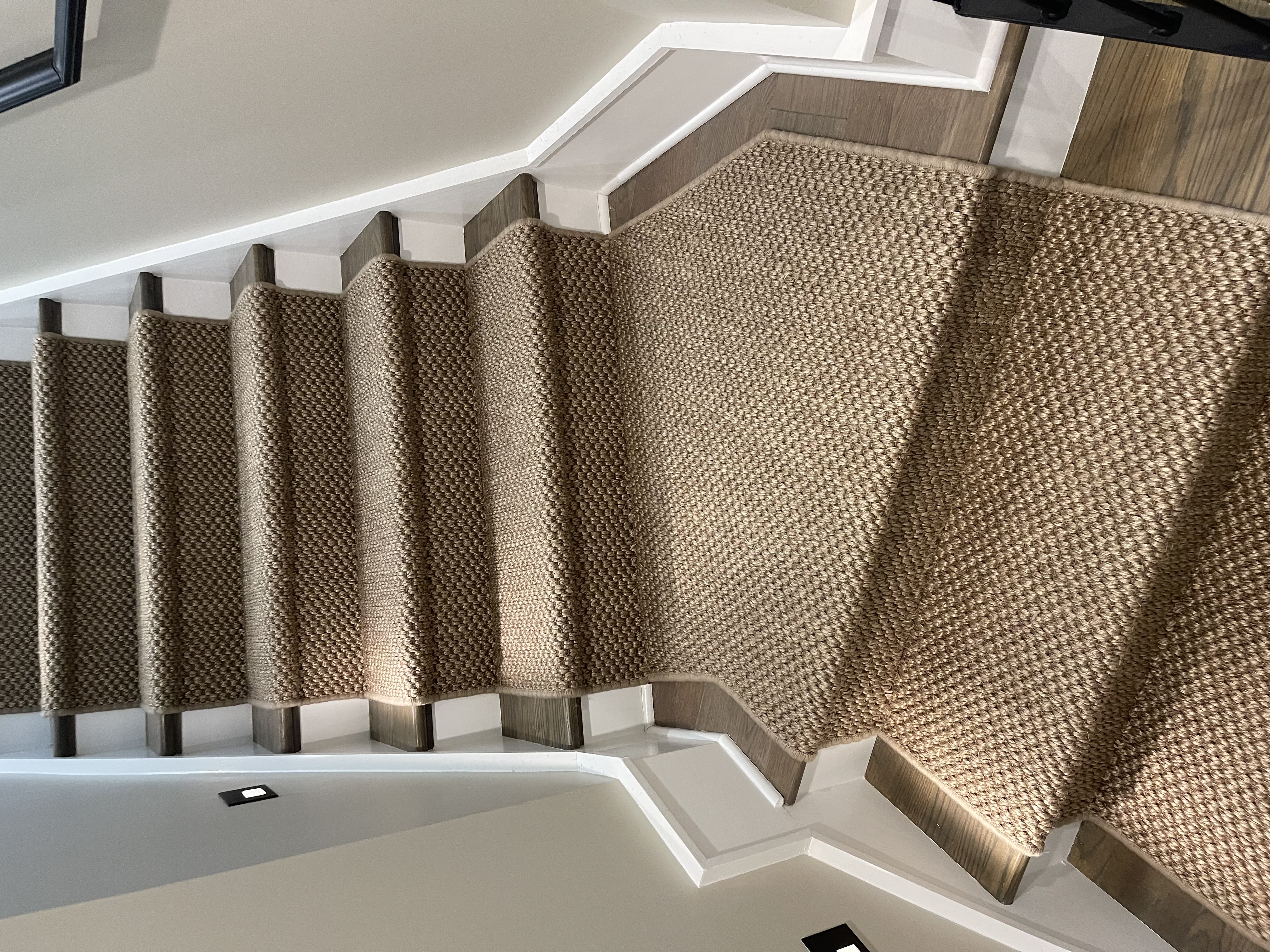 Woven natural runner with white stripe border on dark wood stairs