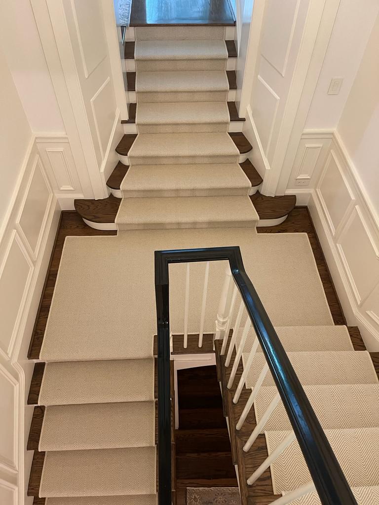 Cream solid runner on multi-flight staircase with wainscoting
