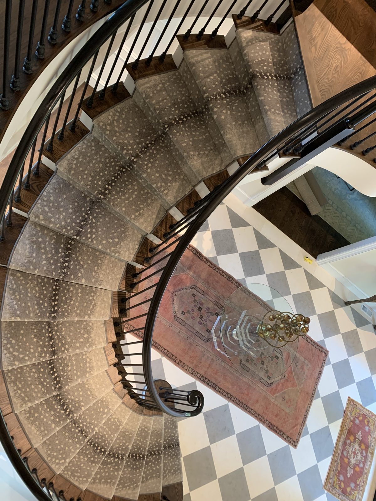 Spiral staircase stair runner above a checkered marble floor