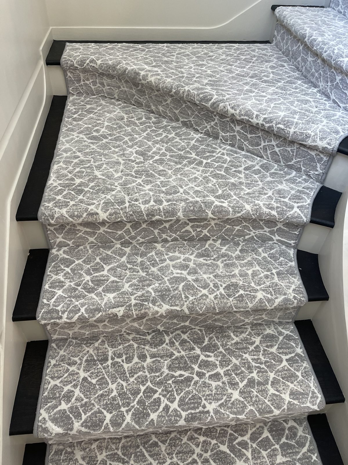 Gray animal-print stair runner with a black border on curved stairs