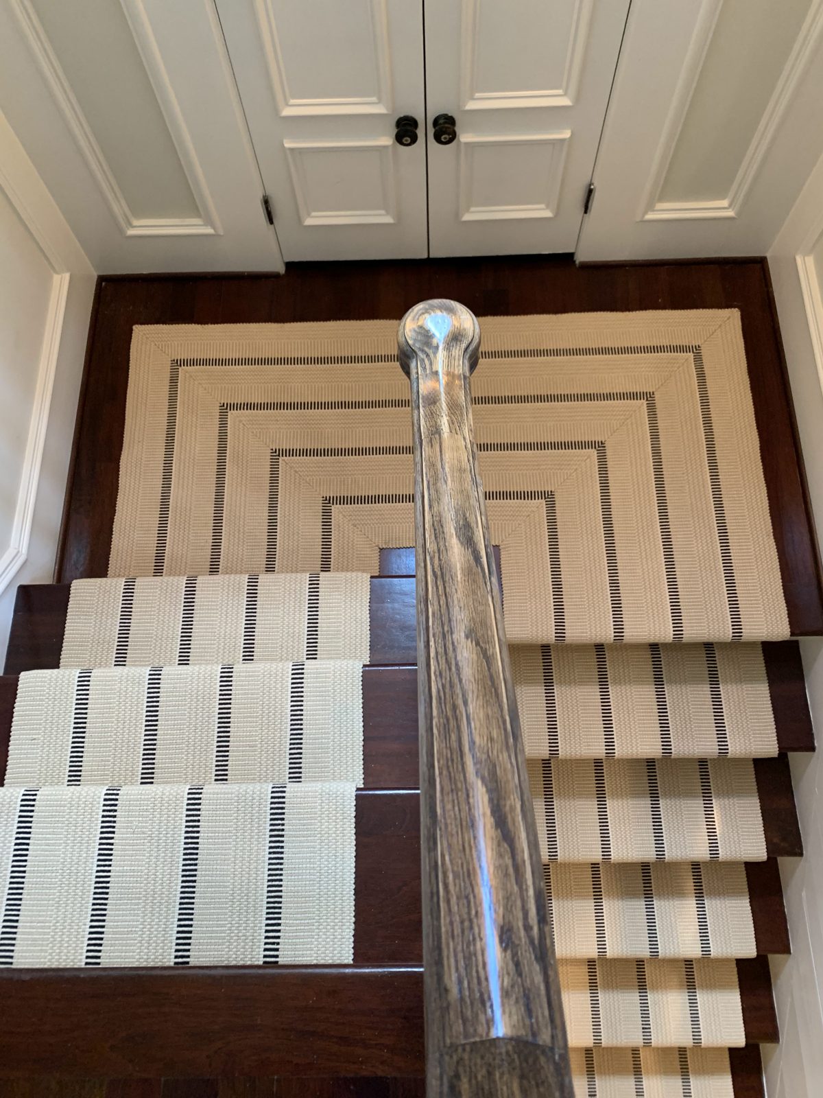 Gray and white striped stair runner to a landing
